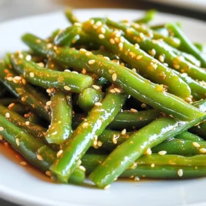 - 1 pound fresh green beans, trimmed and ends removed - 2 tablespoons honey, preferably raw for more flavor - 3 cloves garlic, finely minced - 2 tablespoons low-sodium soy sauce - 1 tablespoon olive oil - &frac12; teaspoon sesame oil for nutty flavor - &frac14; teaspoon red pepper flakes (optional, for a hint of heat) - Salt and freshly ground black pepper to taste - Toasted sesame seeds for garnish - Green Beans: These provide fiber, vitamins A and C, and minerals like manganese. They help support heart health and digestion. - Honey: Raw honey has antioxidants that can boost your immune system. It adds a natural sweetness that complements the garlic. - Garlic: This adds flavor and has health benefits. Garlic can help lower blood pressure and improve cholesterol levels. - Low-Sodium Soy Sauce: This adds umami flavor without too much salt, making it great for seasoning. - Olive Oil: A heart-healthy fat, it helps to absorb nutrients from the veggies. - Sesame Oil: This oil enhances the dish with a rich, nutty flavor, making it even more appealing. - Red Pepper Flakes: They add a spicy kick, enhancing the flavor profile of the dish. - Green Beans: You can use snap peas or asparagus for a different texture. - Honey: Maple syrup works well for a vegan option, providing a similar sweetness. - Garlic: Garlic powder can be used, though fresh garlic is best for flavor. - Soy Sauce: Tamari is a gluten-free alternative that offers the same salty flavor. - Olive Oil: Avocado oil or vegetable oil can be used if you prefer. - Sesame Oil: If unavailable, you can skip it or use a little extra olive oil. - Red Pepper Flakes: If you prefer no heat, simply omit them. {{ingredient_image_2}} 1. Rinse the green beans: Start by rinsing 1 pound of fresh green beans under cold water. This helps remove any dirt. 2. Trim the ends: Use kitchen scissors or a knife to remove both ends of the beans. This step is simple but makes a big difference. 3. Prepare an ice bath: Fill a bowl with cold water and ice cubes. This will keep your beans bright and crisp. 4. Blanch the green beans: Boil a pot of water. Once it&rsquo;s boiling, add the beans and cook for 3-4 minutes. They should turn a vibrant green. 5. Ice bath plunge: Drain the beans and quickly place them in the ice bath. This stops the cooking and keeps them crunchy. 1. Make the sauce: In a small bowl, mix 2 tablespoons of honey, 3 finely minced garlic cloves, 2 tablespoons low-sodium soy sauce, 1 tablespoon olive oil, and &frac12; teaspoon sesame oil. Add &frac14; teaspoon of red pepper flakes if you want some heat. Whisk until smooth. 2. Heat the skillet: Place a large skillet over medium heat. Once hot, add the blanched green beans. Saut&eacute; for 2-3 minutes until warmed through. 3. Add the sauce: Pour the honey garlic sauce over the warm beans. Toss gently to coat them evenly. Cook for another 3-4 minutes to let the sauce thicken. 4. Season to taste: Sprinkle salt and freshly ground black pepper over the beans. Taste and adjust as needed. 5. Serve: Remove the skillet from heat. Transfer the honey garlic green beans to a serving platter. - Garnish: Sprinkle toasted sesame seeds on top for crunch and visual appeal. - Presentation: Use a white serving dish to highlight the colors of the beans and sauce. - Pairing: These green beans pair well with grilled chicken, fish, or tofu for a complete meal. Enjoy this dish fresh for the best flavor and texture! To make your honey garlic green beans pop, use fresh ingredients. Fresh green beans taste better and have more crunch. Raw honey has a richer flavor than processed honey. For an extra kick, add more red pepper flakes. You can also drizzle a bit of lemon juice before serving for brightness. Blanching the green beans helps keep their bright color. This method also makes them tender yet crisp. After blanching, a quick saut&eacute; in a hot skillet adds a nice gloss. Use medium heat to prevent burning the garlic. Toss the beans gently with the sauce to coat evenly. This ensures every bite is flavorful. Avoid overcooking the green beans. They should stay bright green and crisp. If you skip the ice bath, the beans may lose their vibrant color. Don&rsquo;t add too much salt until the end. Soy sauce already brings saltiness, so taste first. Lastly, don&rsquo;t rush the sauce; let it thicken a bit for better flavor. Pro Tips Choose Fresh Beans: Always select crisp, vibrant green beans for the best flavor and texture. The fresher the beans, the more delightful the dish will be! Perfectly Blanch: Make sure to plunge the beans into ice water immediately after boiling to lock in that bright green color and crispness. Customize the Sauce: Feel free to experiment with additional seasonings or spices in the honey garlic sauce to suit your taste. A splash of rice vinegar can add a nice tang! Serving Suggestions: Pair these green beans with grilled chicken or fish for a complete meal, or serve them as a vibrant side dish at your next gathering. {{image_4}} You can easily add protein to your honey garlic green beans. Chicken, shrimp, or tofu work well. For chicken, slice it into thin strips. Cook it in the skillet before adding green beans. For shrimp, just toss them in with the beans. Tofu can be cubed and saut&eacute;ed until golden before mixing. This adds heartiness to the dish. Switching flavors can make this dish new each time. Try adding ginger for a spicy kick. You can also use lime juice instead of soy sauce for a zesty taste. Adding a splash of balsamic vinegar can give it a sweet tang. Experimenting with flavors keeps your meals exciting and fresh. Using seasonal ingredients enhances flavor and freshness. In spring, add asparagus for a crunchy texture. In summer, mix in cherry tomatoes for a burst of sweetness. During fall, you can swap green beans for Brussels sprouts. Each season offers unique tastes that can elevate your honey garlic green beans. Once you finish your meal, let the honey garlic green beans cool down. Place them in an airtight container. Store the container in the fridge. They will keep well for about 3 to 4 days. If you want to enjoy your dish later, make sure to seal it tightly. This helps retain the flavor and texture. When you're ready to eat your leftovers, you have a few options. The best method is to use a skillet. Heat it over medium heat, then add the beans. Stir them gently until they are warm. You can also use a microwave. Place the beans in a bowl and cover with a microwave-safe lid. Heat for about 1 to 2 minutes. Check if they are warm enough, then enjoy! If you want to keep your honey garlic green beans longer, freezing is a great option. First, cool the beans completely. Then, place them in a freezer-safe bag. Make sure to remove as much air as possible. Label the bag with the date. These beans can last for up to 3 months in the freezer. When you are ready to eat them, thaw the beans in the fridge overnight. Reheat them as mentioned earlier for the best taste. You can pair honey garlic green beans with many dishes. They work well with grilled chicken or fish. They also complement rice or quinoa nicely. For a complete meal, serve them with a protein and a starch. The sweet and savory flavor of the beans adds balance to your plate. Yes, you can easily make this recipe vegan. Simply replace honey with maple syrup. This swap keeps the sweet flavor intact. The rest of the ingredients are already plant-based. Use low-sodium soy sauce and olive oil as they are. This way, you can enjoy the same great taste without animal products. Honey garlic green beans can last for about 3 to 5 days in the fridge. Store them in an airtight container to keep them fresh. When you reheat, give them a quick saut&eacute; to regain their crispness. If they start to lose color or texture, it&rsquo;s time to toss them. In this article, we explored the ingredients, preparation, and serving ideas for honey garlic green beans. We discussed the benefits of each ingredient and offered substitutions. You learned cooking steps and tips for enhancing flavors. We also shared variations and storage info to keep your dish fresh. For great meals, remember these key points. Enjoy your cooking and have fun with flavors!